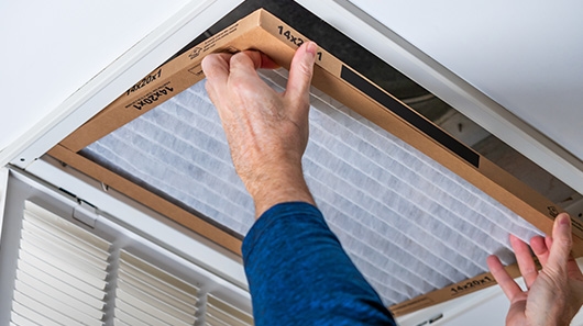 Person replacing air filter in home
